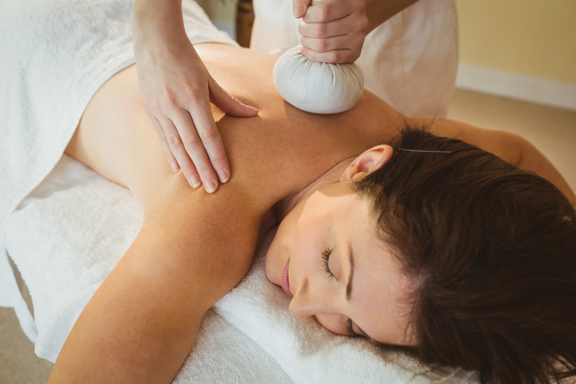 Young woman getting herbal compress massage